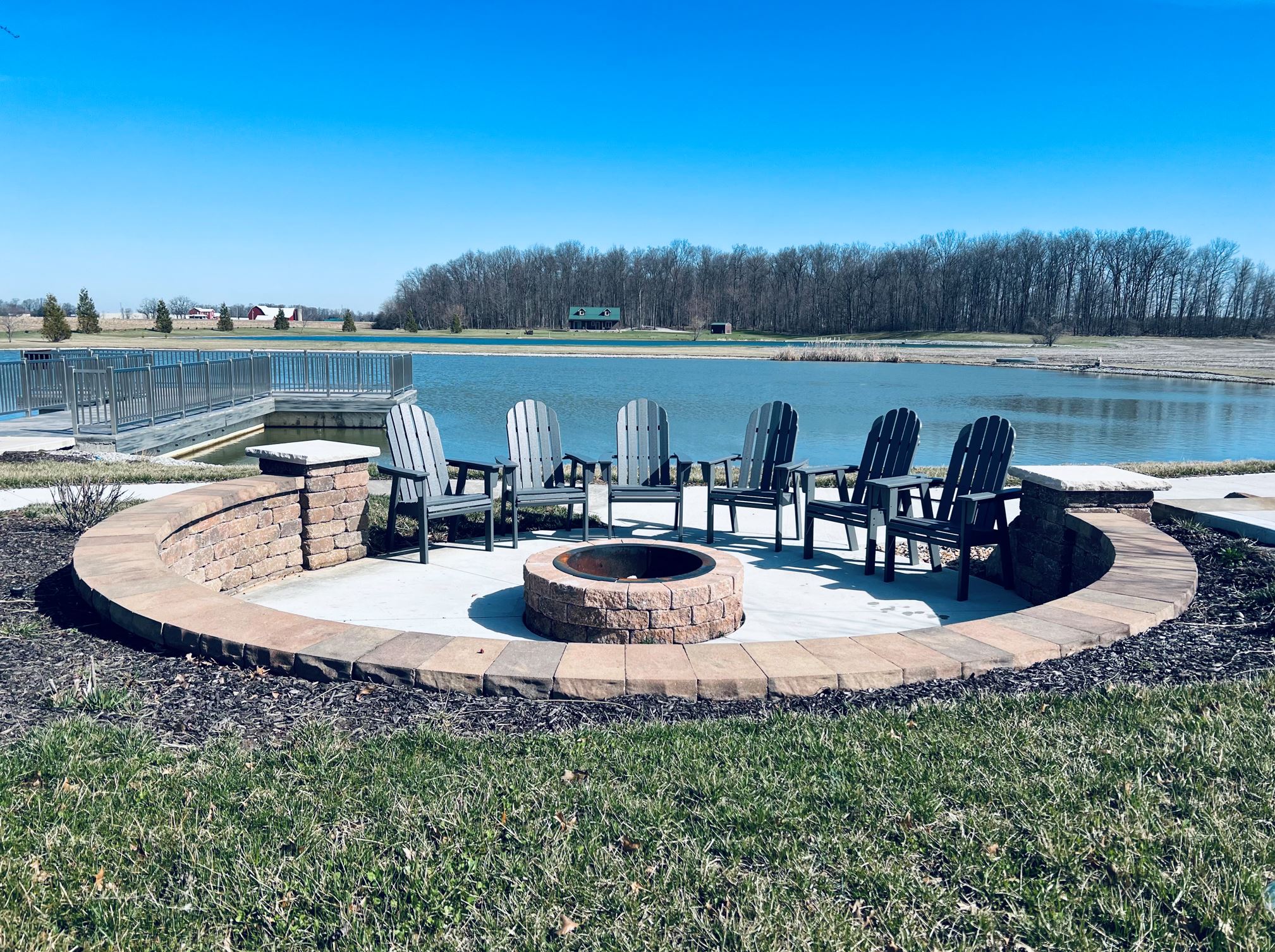 wood firepit facing pond with chairs